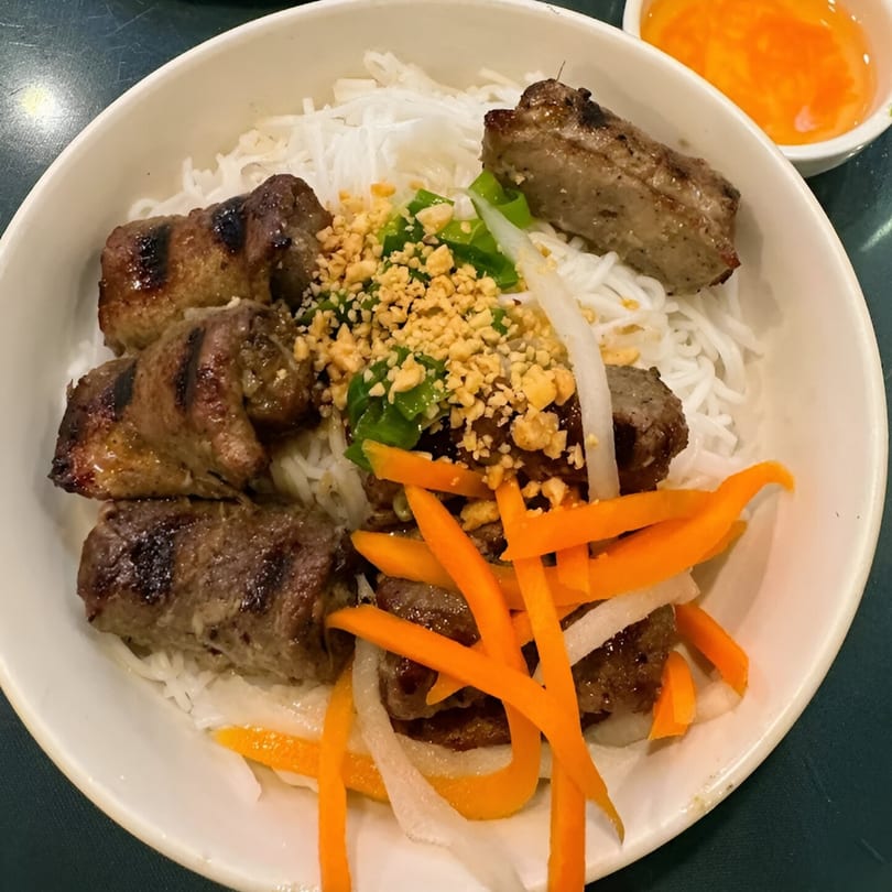 Pho Hoai's Vietnamese vermicelli bowl with grilled pork, peanuts, carrots, and a side of sauce.
